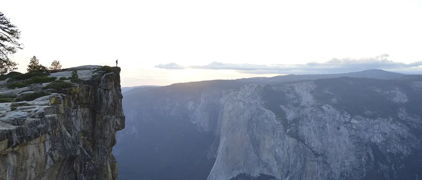 A lone figure standing at the edge of Taft Point above Yosemite Valley